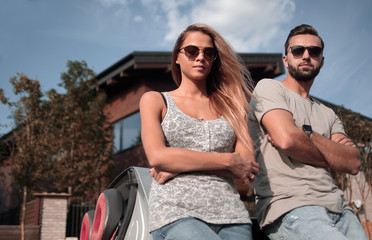 Naklejka premium bottom view.beautiful couple standing near a convertible car