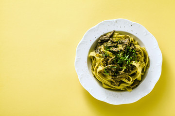 fresh italian pasta tagliatelle with porcini mushrooms in a plate on a white background