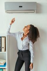 attractive african american businesswoman standing under air conditioner in office