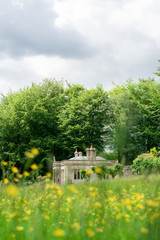 Old British Building in Summer Through Meadow