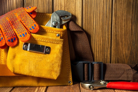Tools and instruments in leather bag on wooden background.