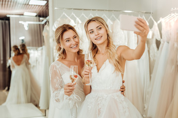 Two brides taking a selfie in a wedding salon.