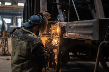 Welder repairs freight car in railway depot