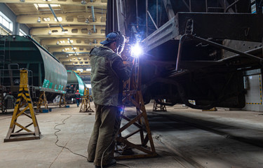 Welder repairs freight car in railway depot