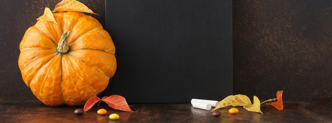 Fall chalkboard background with pumpkin, leaves and candies.