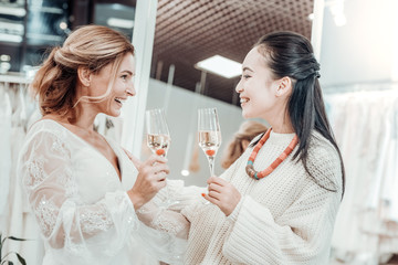 Smiling bride drinking champagne with her maid of honour.