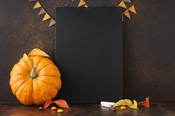Autumn background with chalkboard, pumpkin, yellow leaves.