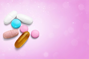 pills and capsules on a pink background close-up