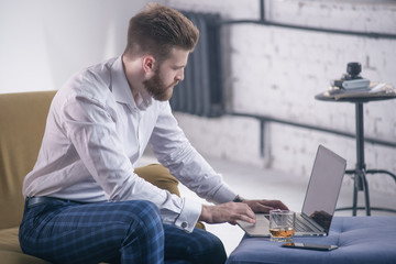 Bearded hipster boy professional freelance social media content writer keyboarding on laptop...