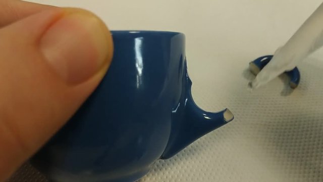 Repair a coffee cup with glue. The spout applies a drop of glue to the point, then the broken handle is placed and held in place while waiting for the glue to set. 25Fps