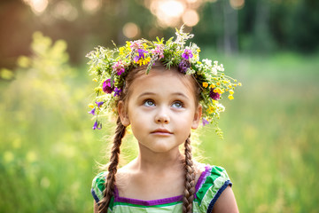  little girl in a wreath of wild flowers in summer