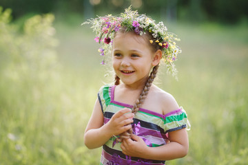  little girl in a wreath of wild flowers in summer