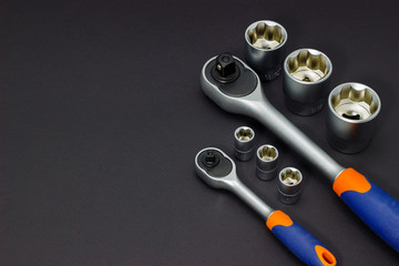A set of tool heads for loosening screws, bolts and nuts. Ratchet screwdriver. Dark background.