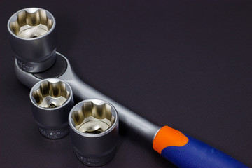 A set of tool heads for loosening screws, bolts and nuts. Ratchet screwdriver. Dark background.