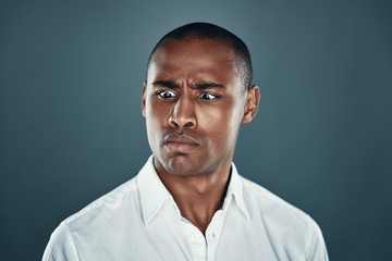 Cross eyed man. Handsome young African man in shirt making a face while standing against grey background