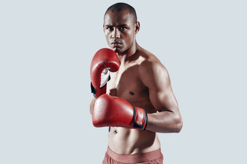 Confident boxer. Handsome young African man in red boxing gloves looking at camera while standing...