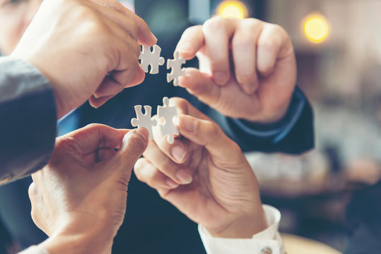 Businessman team work holding two jigsaw connecting couple puzzle piece for matching to goals target, success and start up new project in office, select focus. Business Concept.