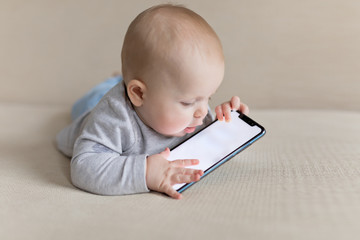 Little baby child is playing with smartphone learning how to communicate with new technologies
