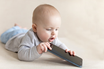 Little baby child is playing with smartphone learning how to communicate with new technologies