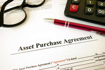 Asset purchase agreement with pen calculator and glasses