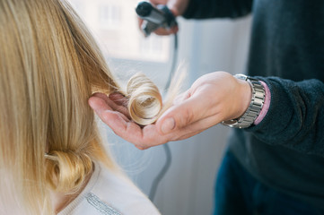 A hairdresser making a haircut for a blonde female client