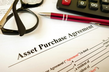 Asset purchase agreement with pen calculator and glasses