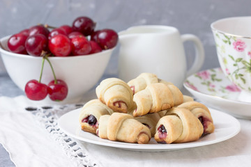 Naklejka na ściany i meble Homemade croissants with cherry jam and fresh cherries on the table.