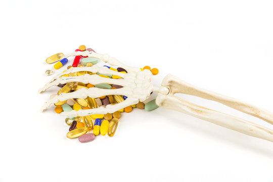 White Bony Skeleton Hand Palm Down Grabbing A Handful Of Pills