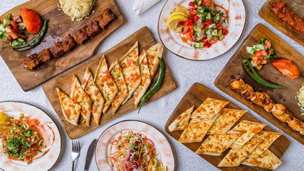 Assorted Turkish foodset on table. Turkish pide with cheese, Turkish pide with vegetables, vegetable salad, turkish kebabs from beef and chicken.