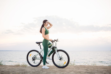 Fototapeta na wymiar Young brunette woman on a bicycle at sunrise.