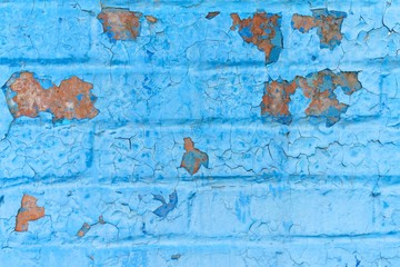 Old grunge brick wall of a background or texture painted in blue paint that cracked under the influence of time and weather