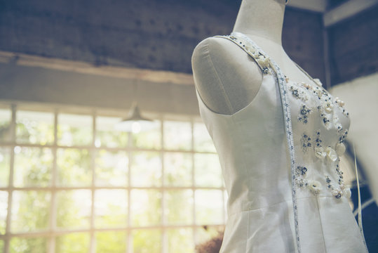 Dressmaker fashion designer make white wedding dresses in mannequins with measure tape for bridal fitting in wedding studio.  Fashionable beauty wedding dress style for pretty female. fashion garment