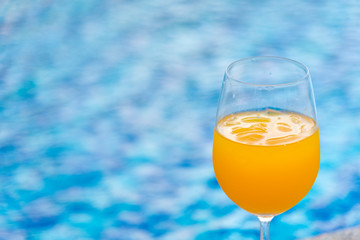 glass of fresh Orange juice on the swimming pool. Tropical Soft drink.