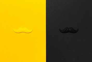 Creative party decoration concept. Black and yellow mustache, props for photo booths, carnival parties on black yellow background top view flat lay copy space Father's day Men's health awareness month