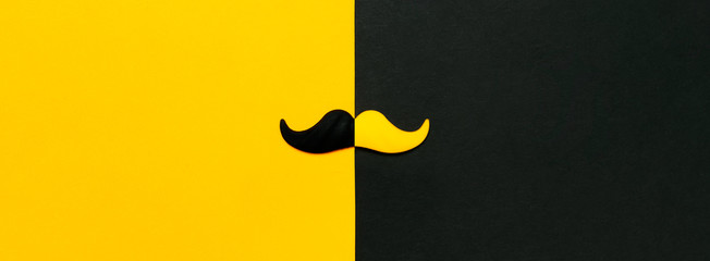 Creative party decoration concept. Black and yellow mustache, props for photo booths, carnival parties on black yellow background top view flat lay copy space Father's day Men's health awareness month