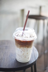 Cup of ice coffee latte on wooden chair background.