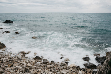 Fototapeta na wymiar Restless sea near the stone coast. Surf. Natural landscape