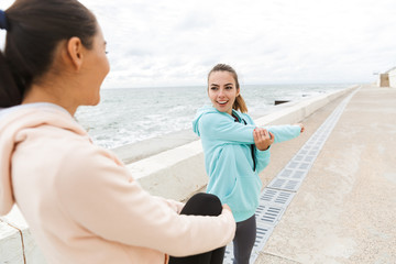 Two attractive young fitness women wearing hoodies