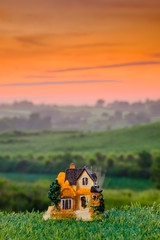 Miniature house on the grass at sunrise. Concept of Travel