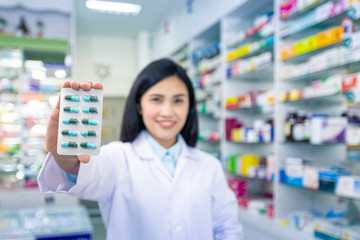 Capsules medicine with female pharmacist in pharmacy background. Health care and medical concept.