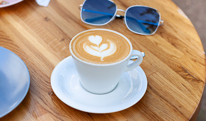 Cup of coffee on the wooden table in cafe outdoor. Breakfast in cafe concept. Close up