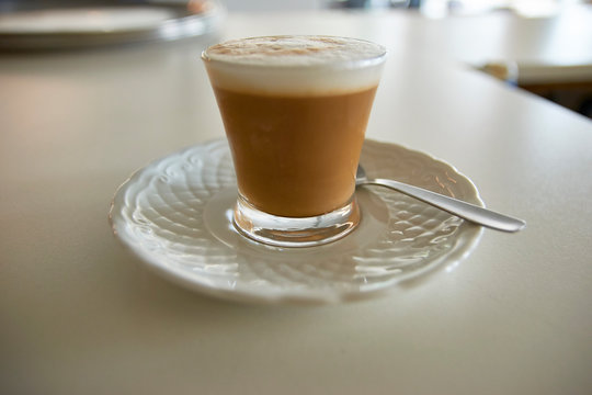 Spanish Cortado (cut) or Italian Macchiato. Traditional coffee espresso mixed with hot foamed milk. Small transparent cup. Morning drink. Cafeteria, restaurant vacation holidays relaxation wake-up.