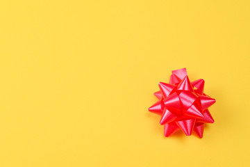 Red bow on a yellow background. Copy space.