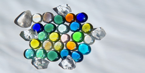 Differently colored glass round crystals and curly shadow on a light background.