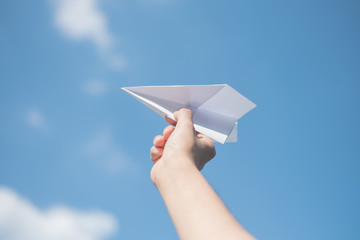 Men's hands holding a white paper rocket with a bright blue background.
