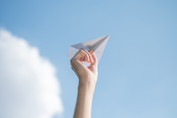 Men's hands holding a white paper rocket with a bright blue background.