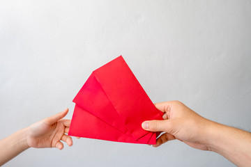 The hands of the men holding the Angpang envelope are standing for the young woman to be a Chinese New Year's Day gift.