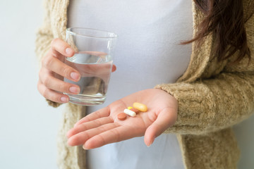 A woman holding a medicine and a glass of water in her hand. Medical and health concepts