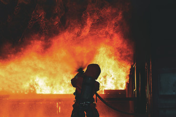 Firefighters water spray with high pressure to fire surround with damaged house, godown....