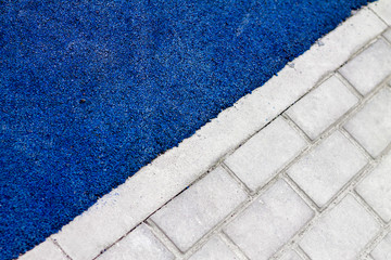 Fototapeta premium bright blue asphalt bordered on a gray brick road; photo shows the contrast and the difference between them